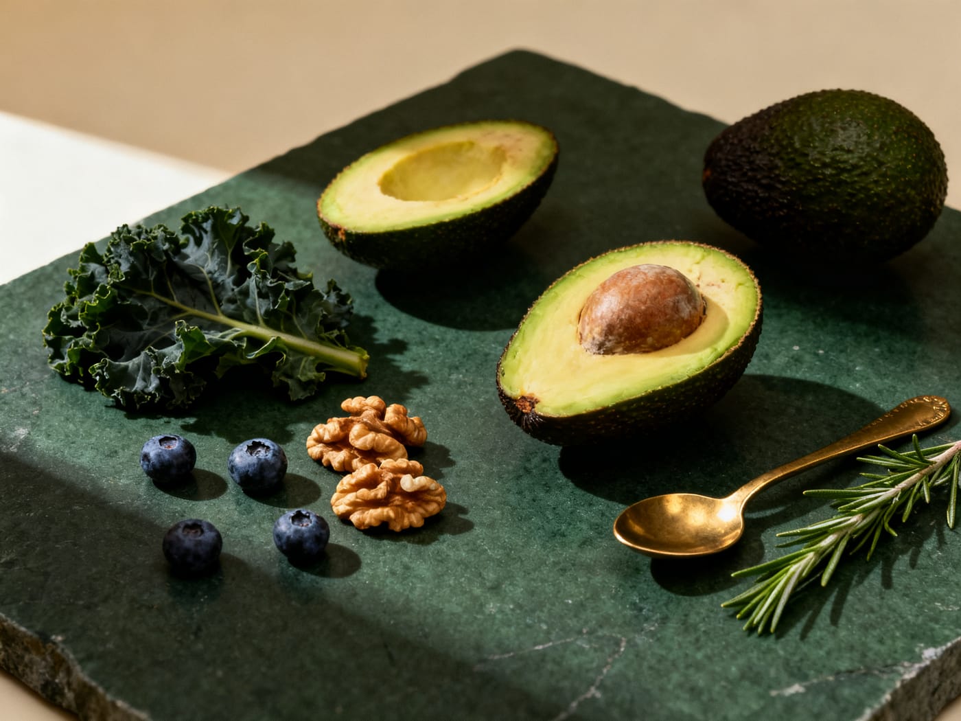 Aguacate, kale, nueces, arándanos y una ramita de romero sobre una tabla de piedra verde